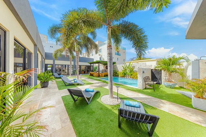 Palm trees, sun loungers and stone pathway surrounding Sea La Vie