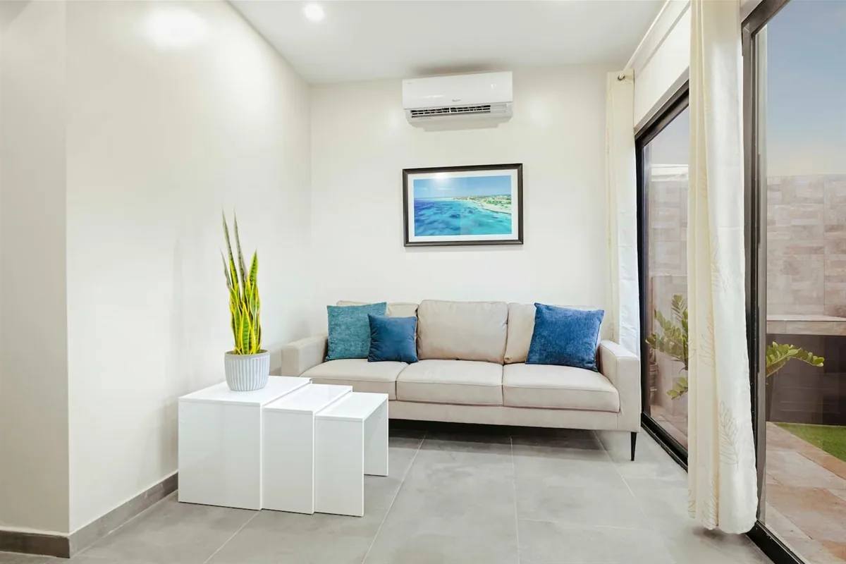 Bright modern living room with cream sofa and white tables inside Sea La Vie Suite 1.
